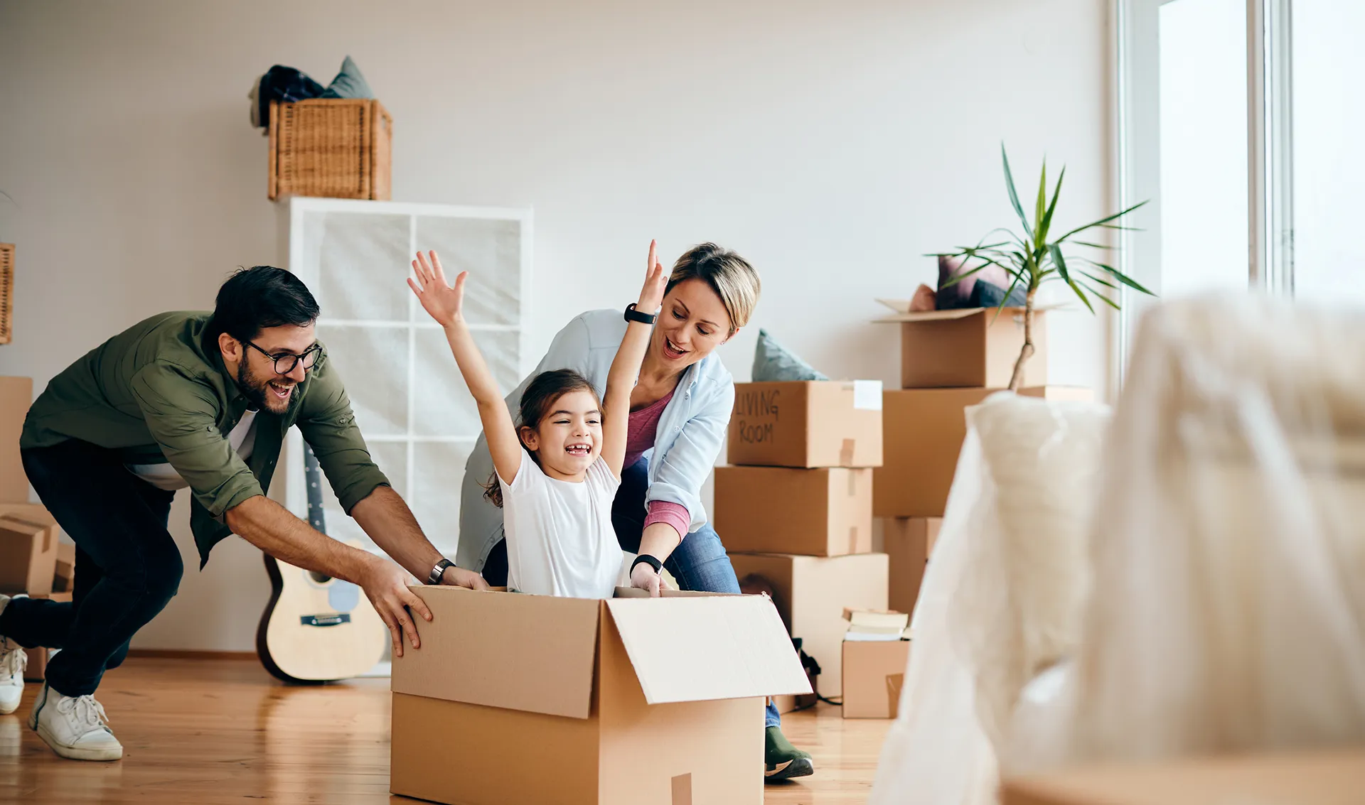 A family playing among moving boxes in a bright new apartment