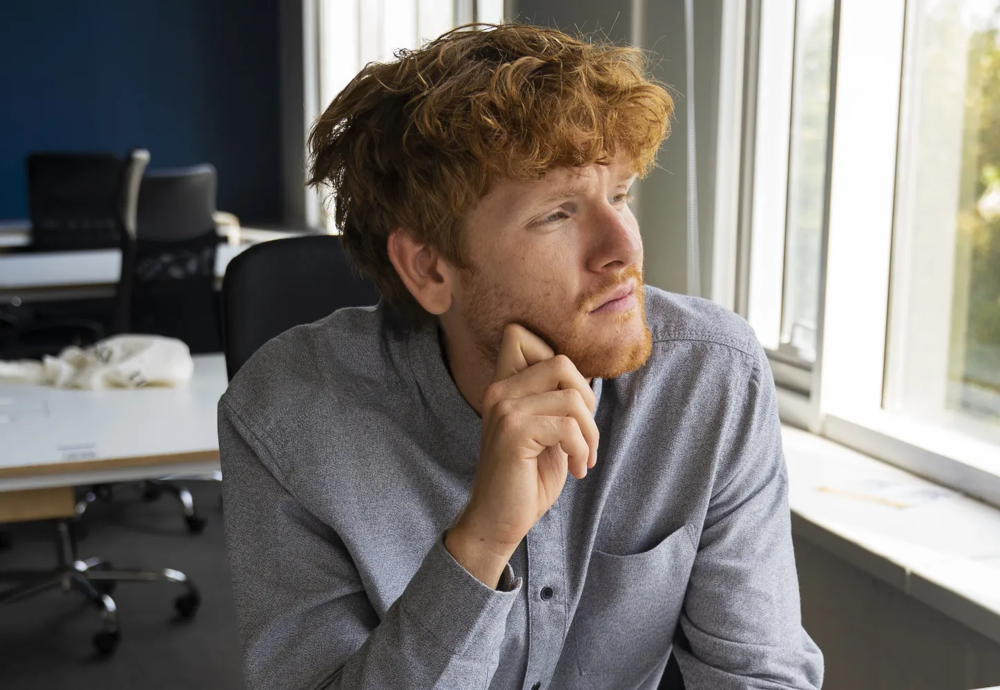 A person looking thoughtfully out of an office window